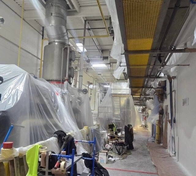 Active food production facility being prepped for painting with equipment masked in plastic
