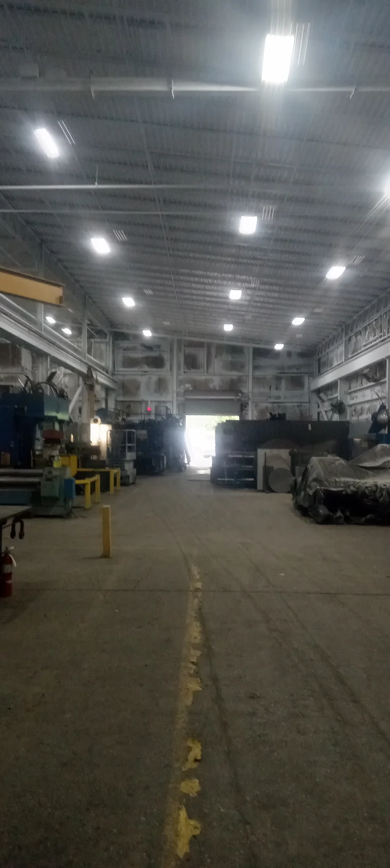 AFC Holcroft fabrication warehouse after repaint — bright white ceiling, trusses, and upper walls over the active shop floor