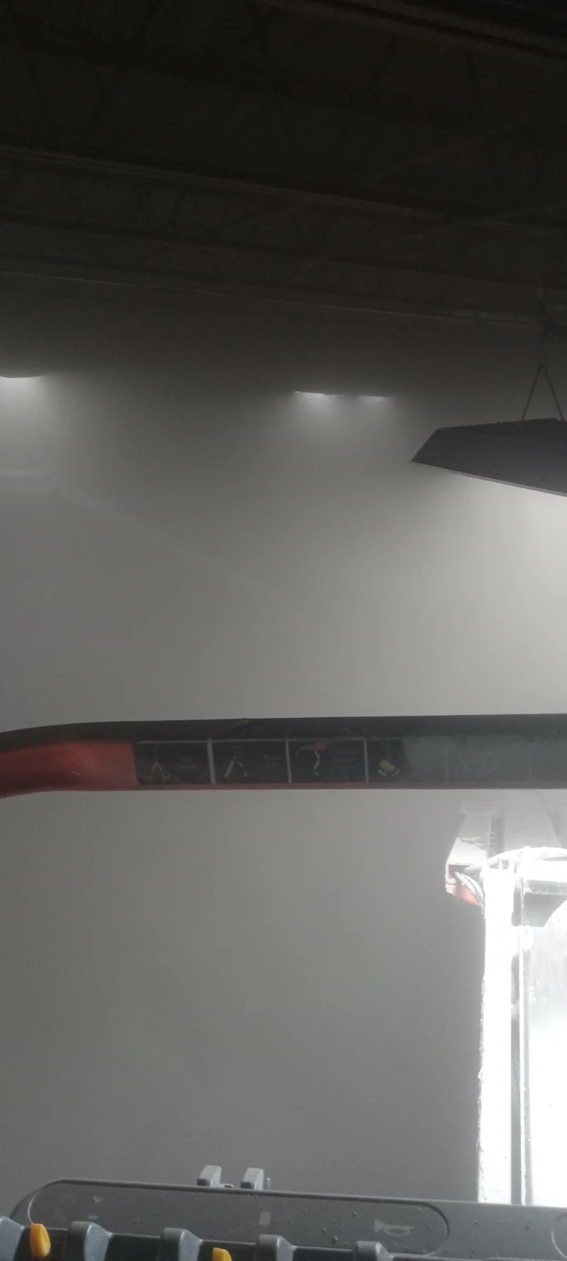 Air lance blow-down in progress — decades of built-up dust clouding the AFC Holcroft ceiling before painting