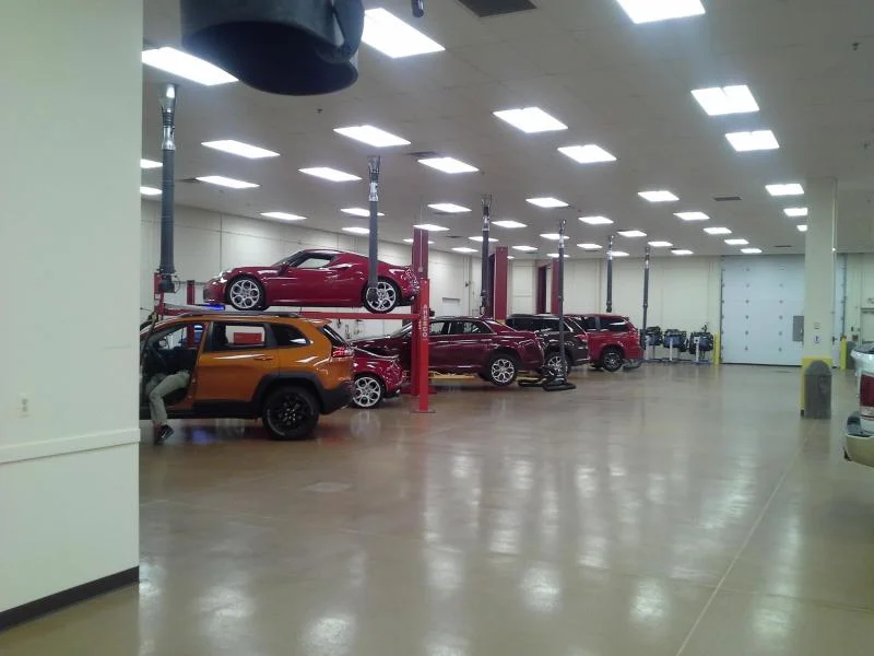 Automotive training facility service bay with vehicles on lifts and freshly painted white walls and ceiling