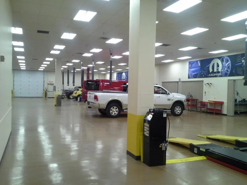 Automotive training facility bay with vehicle on lift, freshly painted columns, and overhead lighting