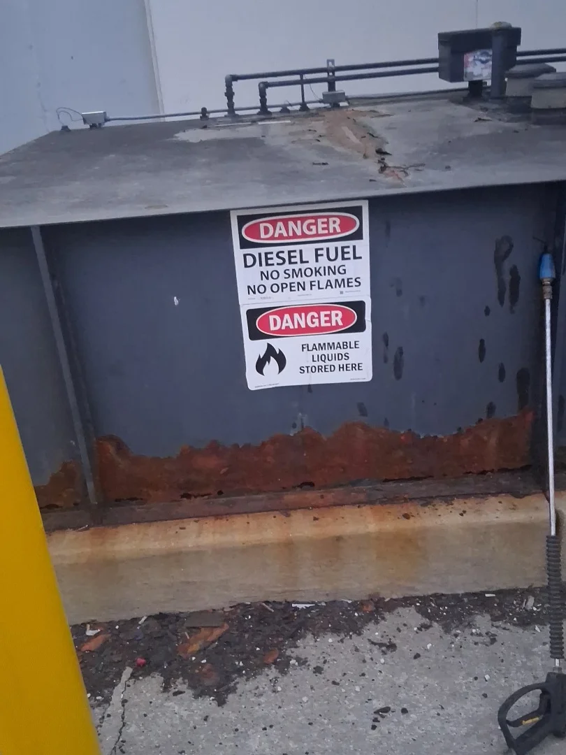 Ground-level fuel tank before service, showing corrosion at the base