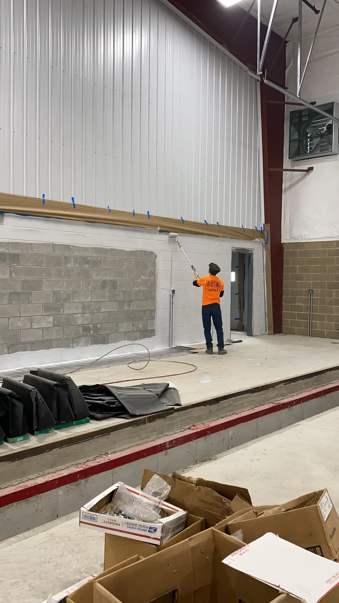 Crew member rolling block fill onto the CMU wall from a raised dock section of the facility