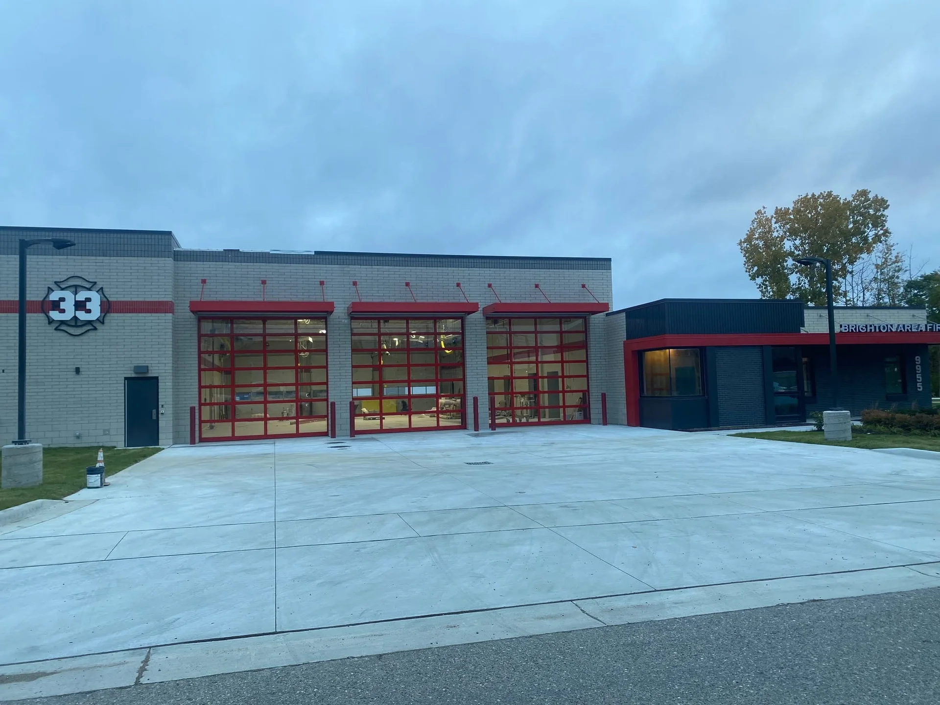 Fire station apparatus bay exterior with red overhead doors and painted brick and trim