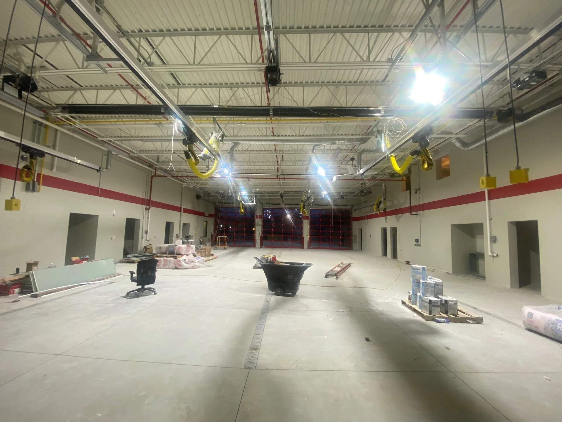 Interior apparatus bay during new construction paint prep, with red accent stripe painted on walls