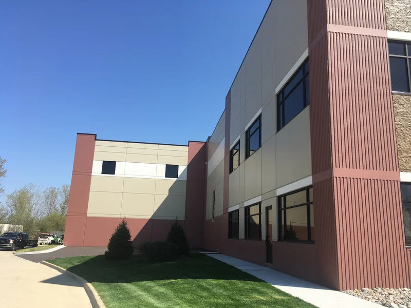 Side elevation of the CMAC Trucking building with repainted tan and white panels, maroon base, and ribbed maroon accent tower