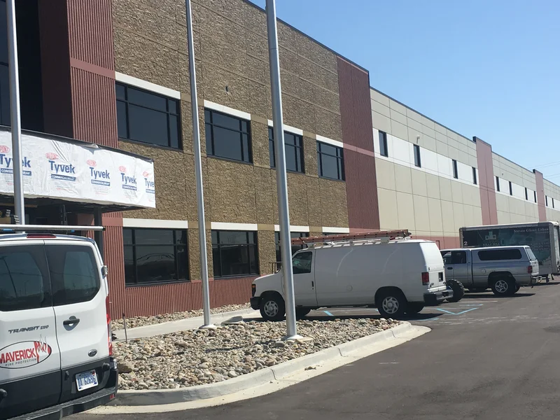 Front of the CMAC Trucking building showing the faux brick finish panels between maroon ribbed columns and tan warehouse walls