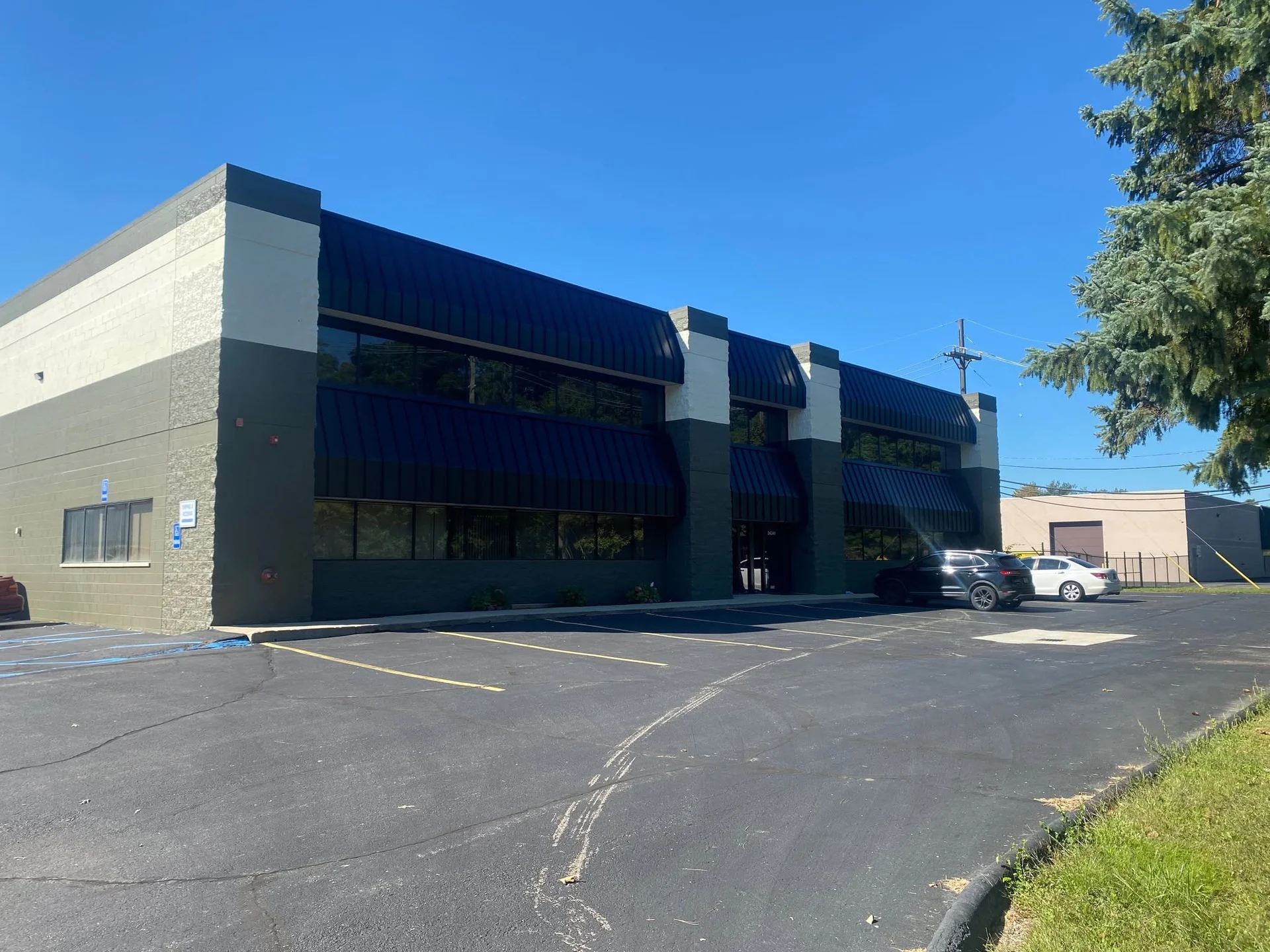 Two-story commercial building exterior with freshly painted tan and dark green block and brick facade