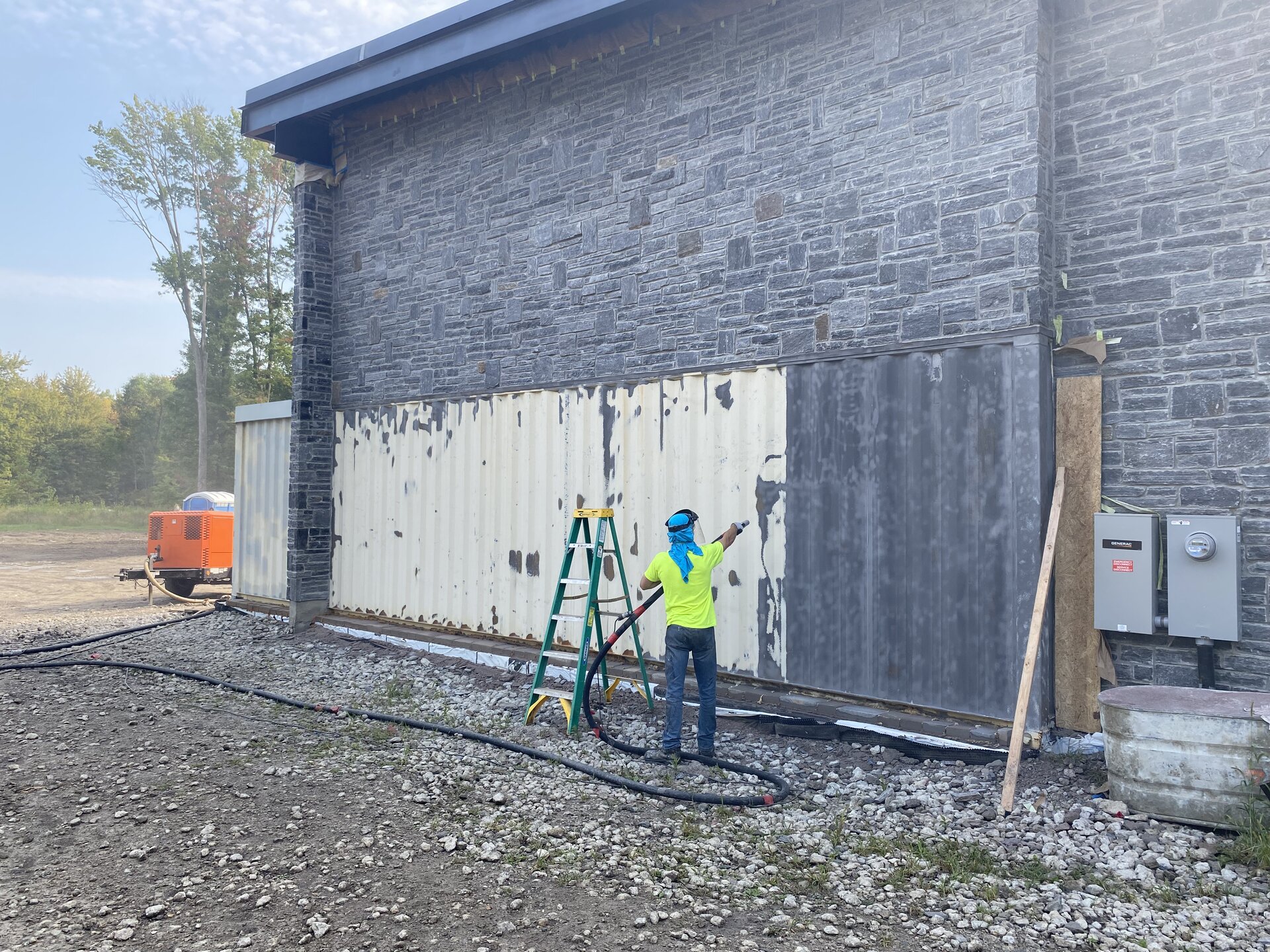 Crew spray applying coating to container exterior wall
