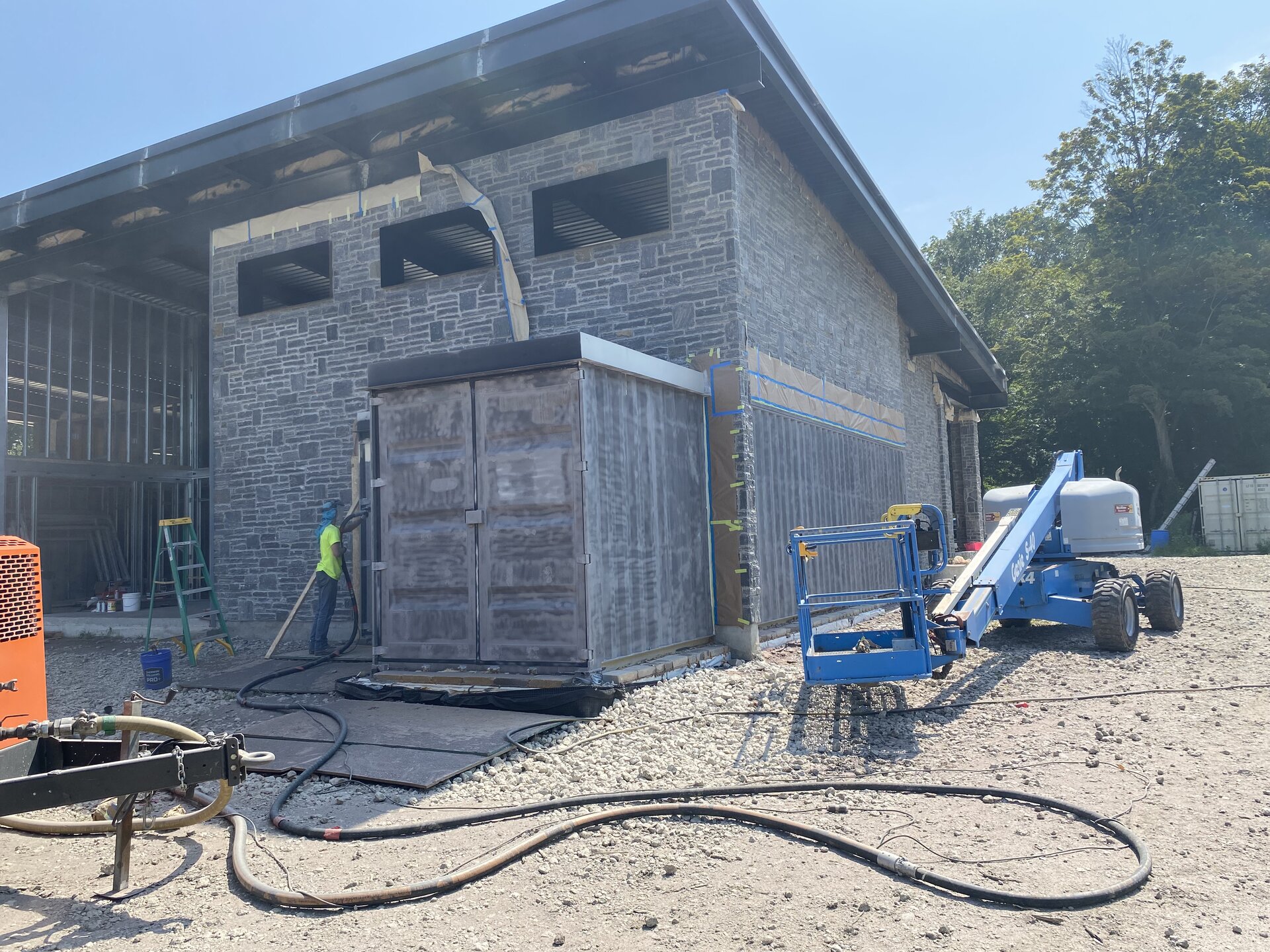 EP crew spray painting shipping containers black with boom lift