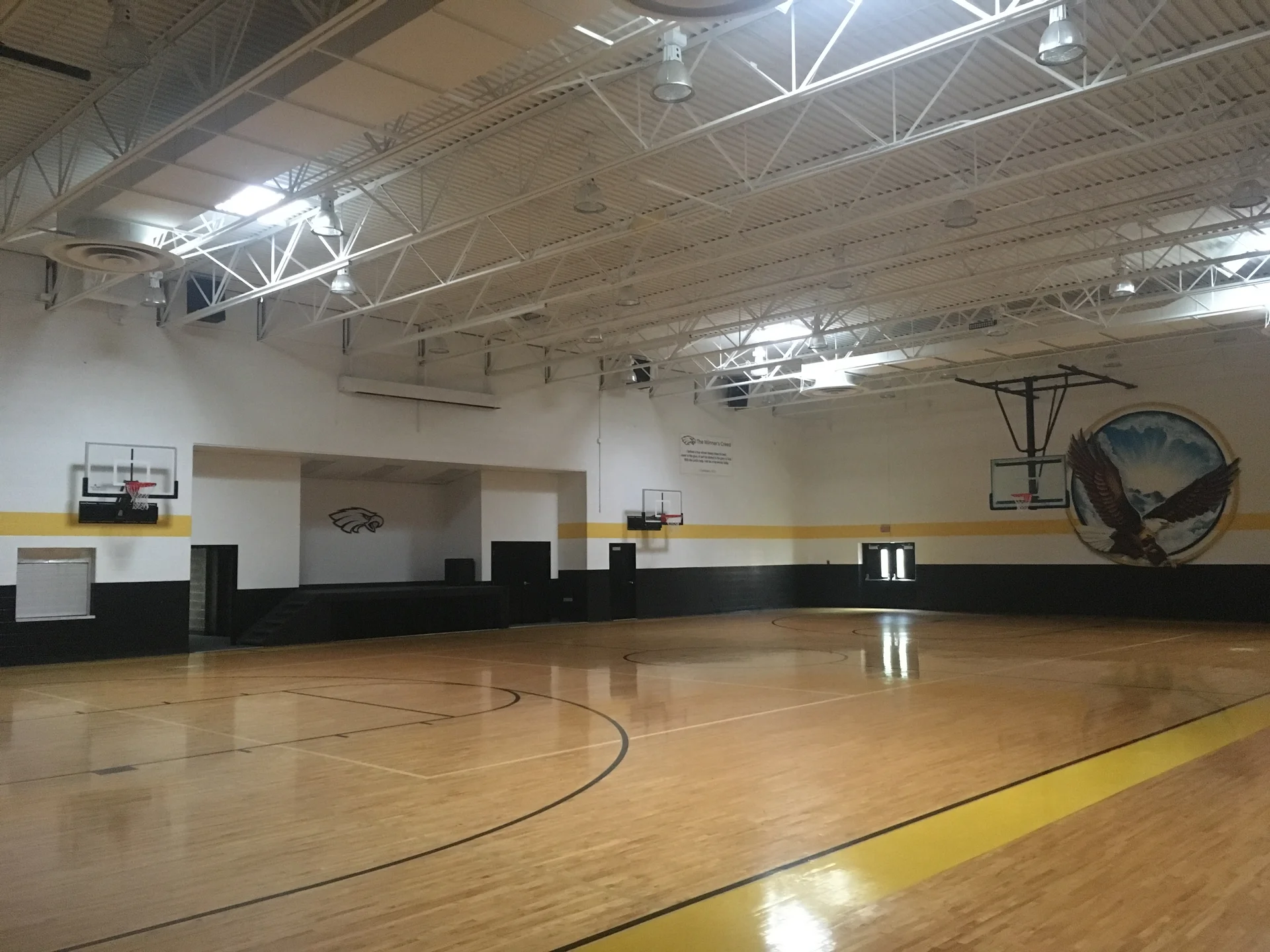 Faith of Davison gymnasium completed — full court view showing black wainscot, gold stripe, and white upper walls