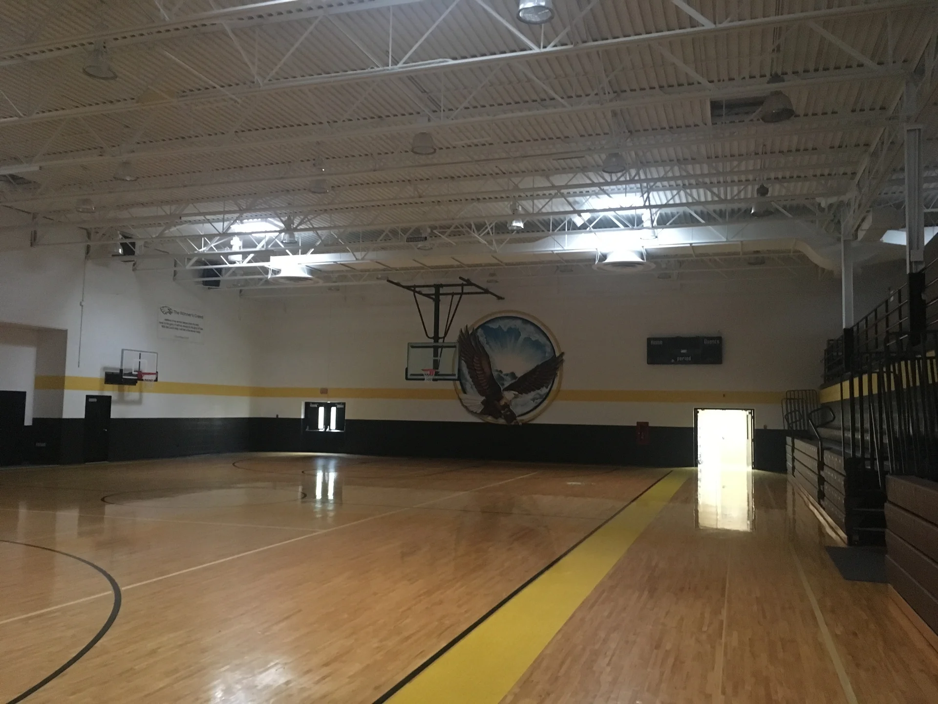 Finished gymnasium at Faith of Davison — opposite end showing bleachers and Eagles mascot mural