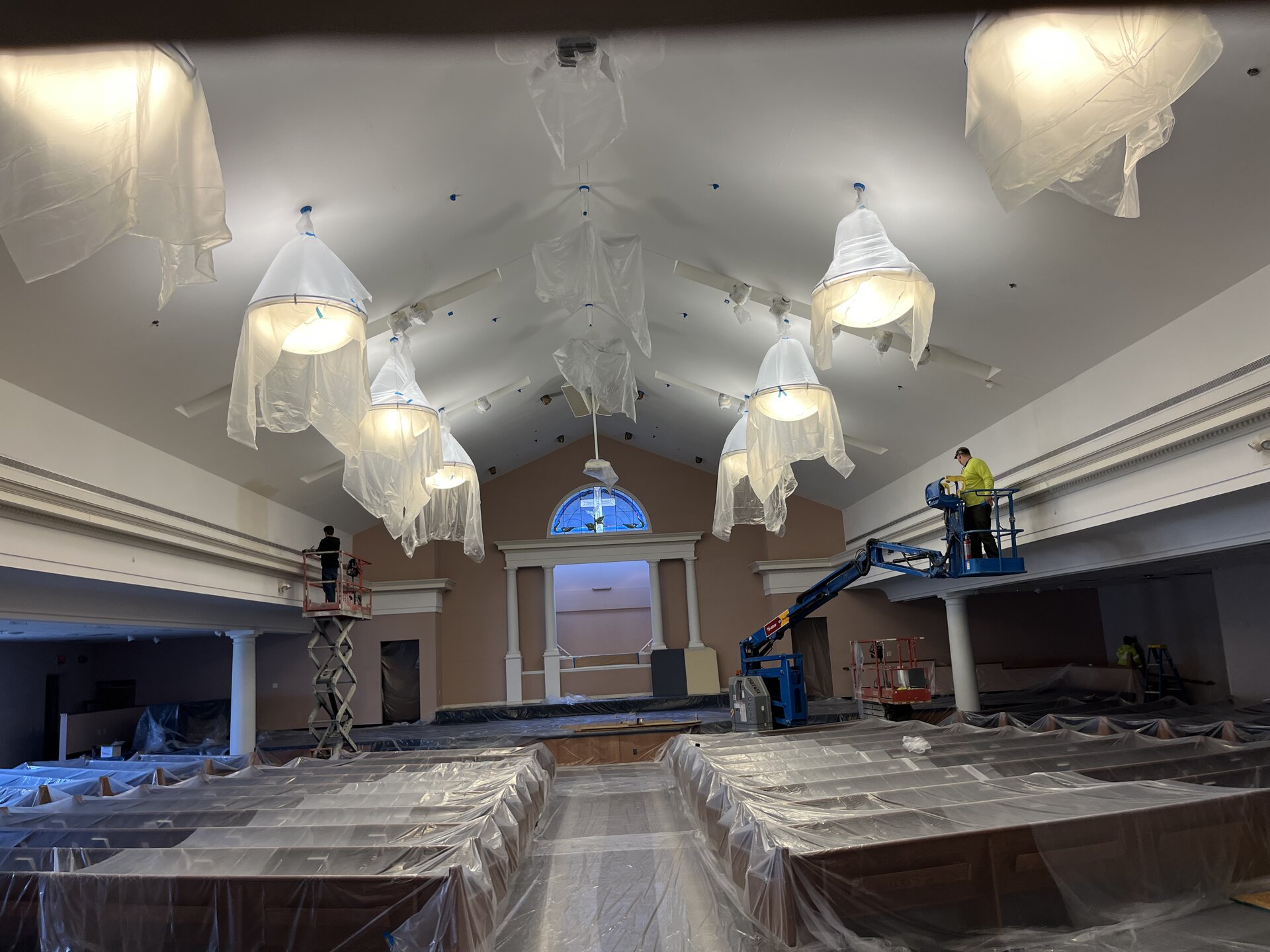 Auditorium ceiling work — boom lift crew painting upper walls and crown