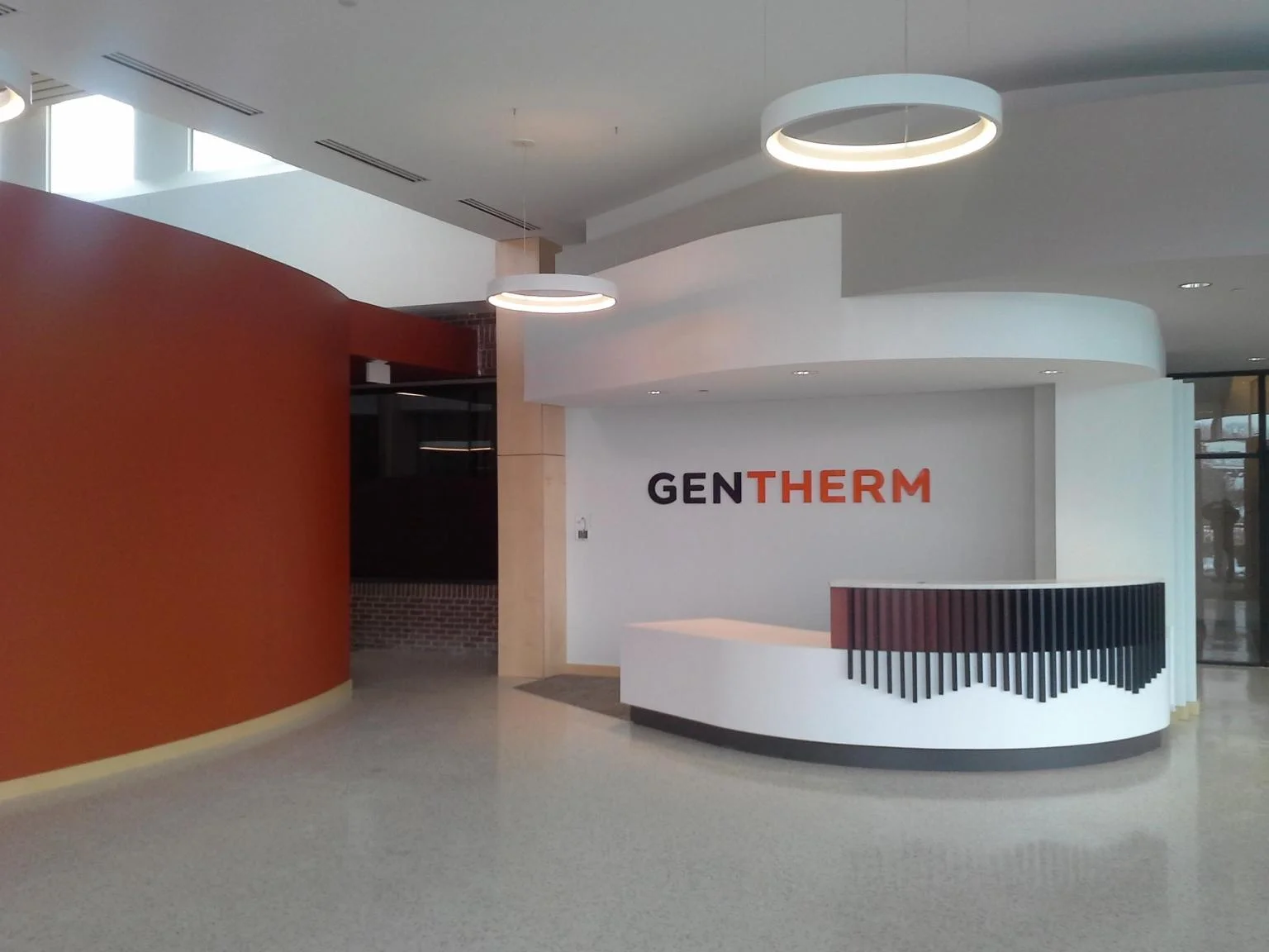 Gentherm office lobby and reception area with freshly painted orange accent wall and white ceiling
