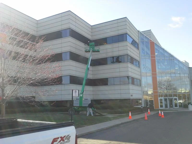 Aerial lift positioned near the building's glass atrium entrance during exterior work