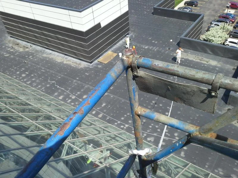 Crew working at the rooftop edge during high-access exterior maintenance