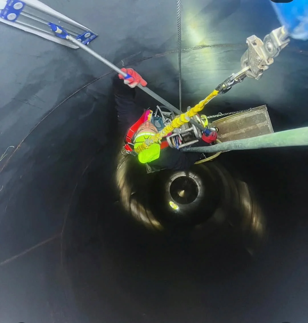 Crew member in full confined space gear descending inside a silo on rope access