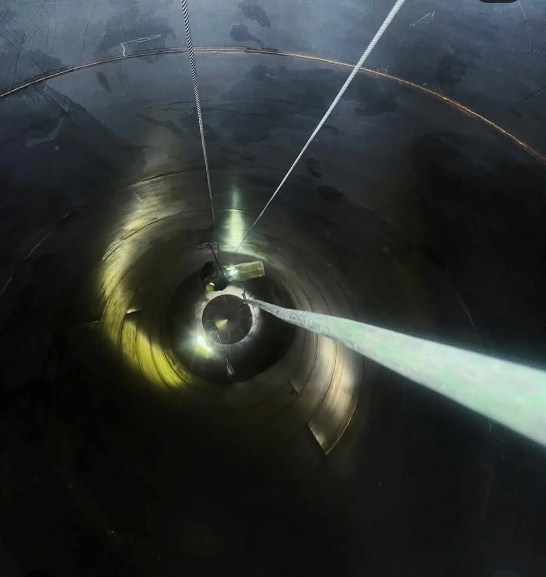 Looking straight down into the silo interior — dramatic depth shot showing the scale of the confined space work