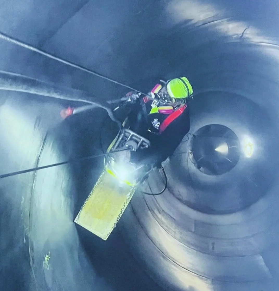Inside a silo — crew member in confined space gear suspended on ropes working the interior walls