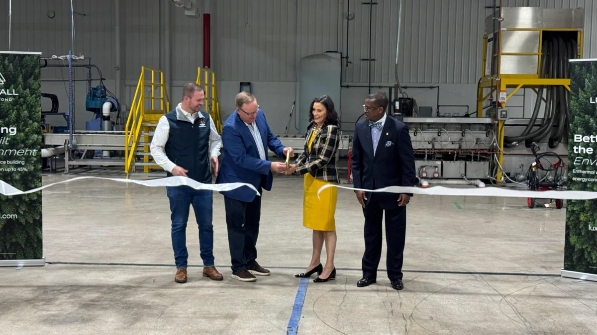 Ribbon-cutting ceremony on the finished LuxWall plant floor, glass manufacturing machinery in the background