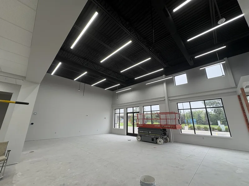 Pella commercial interior with black-painted open ceiling and exposed steel above freshly painted light gray walls and storefront windows