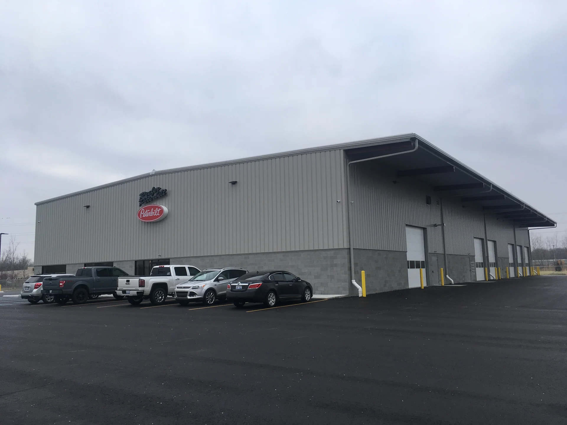 Peterbilt dealership building exterior with freshly painted tan metal panels and gray block base