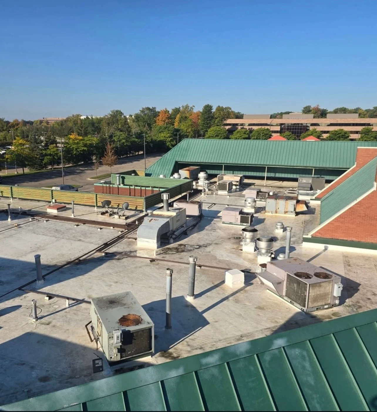 Wide rooftop view of the shopping center showing HVAC units and standing-seam roof sections before cleaning
