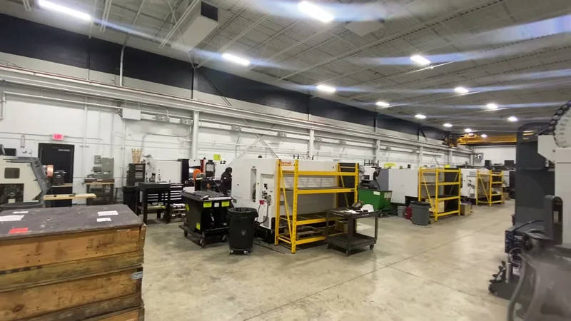 SRS Manufacturing machine shop after repaint — bright white ceiling, walls, and steel over rows of CNC machines
