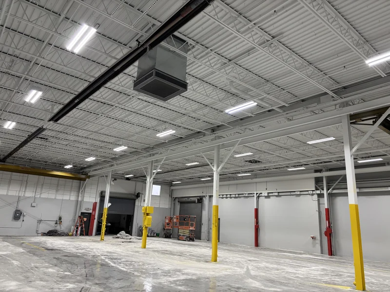 Superior Cam warehouse interior with freshly painted white dryfall ceiling, steel trusses, and yellow safety-painted column bases
