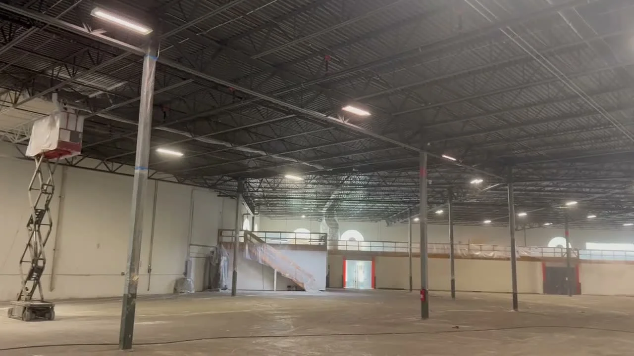 Virginia Tile warehouse interior with exposed steel deck ceiling, arched windows, and scissor lift access