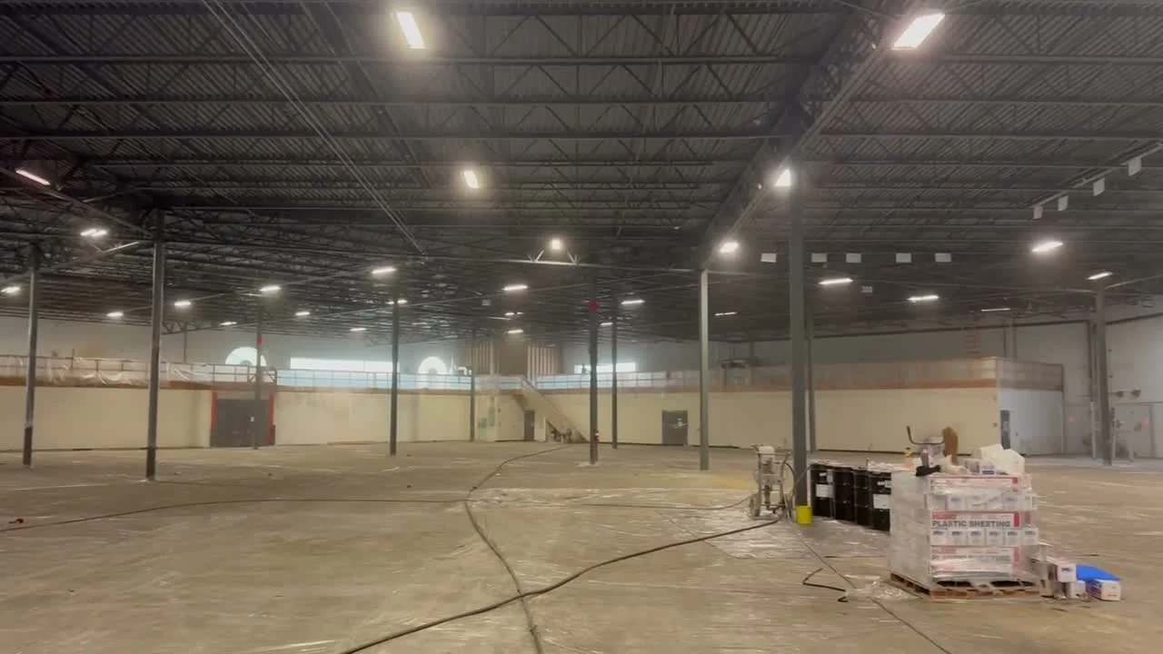 Warehouse floor protected with plastic sheeting, with paint materials and equipment staged for the job