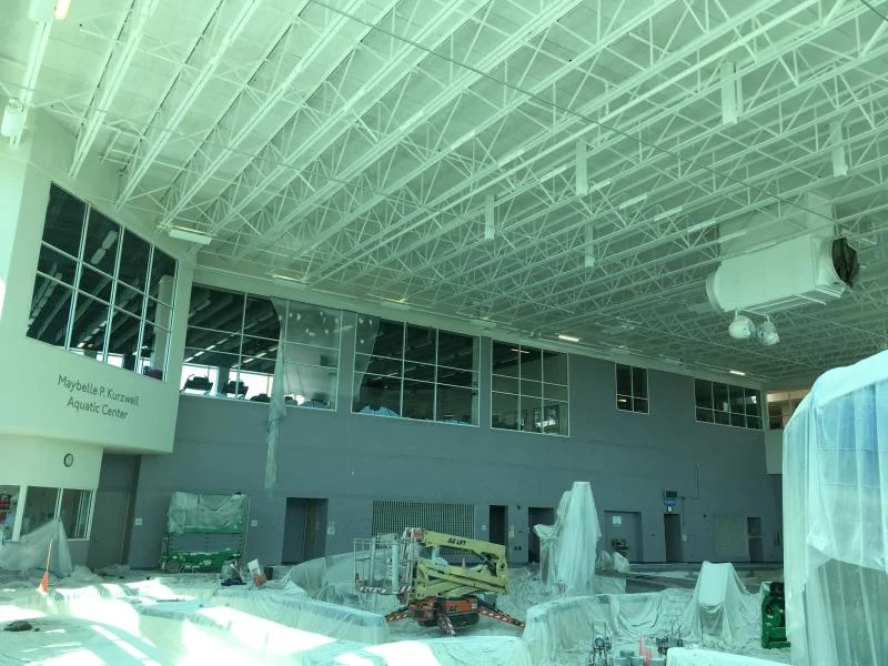 YMCA aquatic center pool deck with freshly painted white exposed steel roof trusses overhead